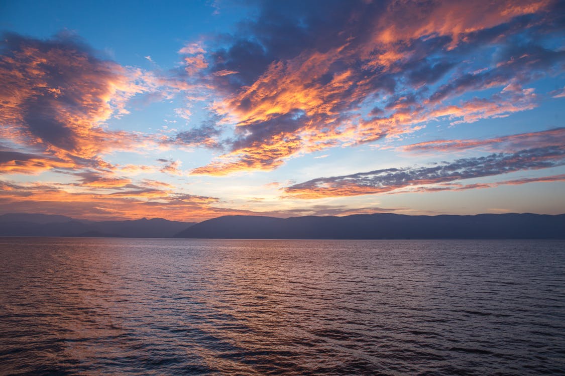 Sonnenuntergang auf dem Meer mit orangefarbenen Wolken