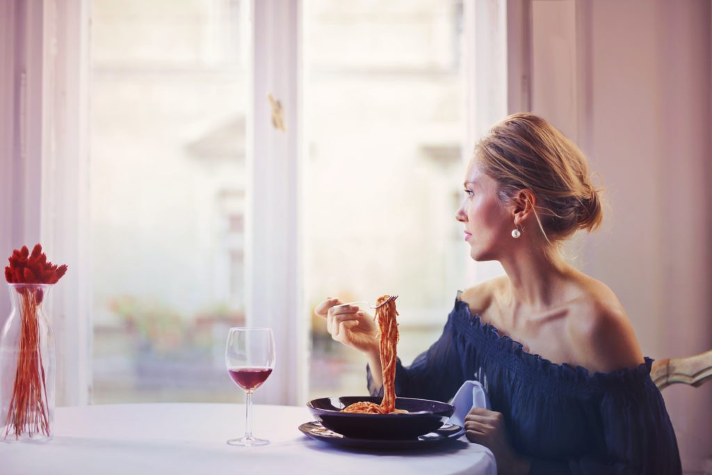 Une jeune femme mange en regardant par la fenêtre
