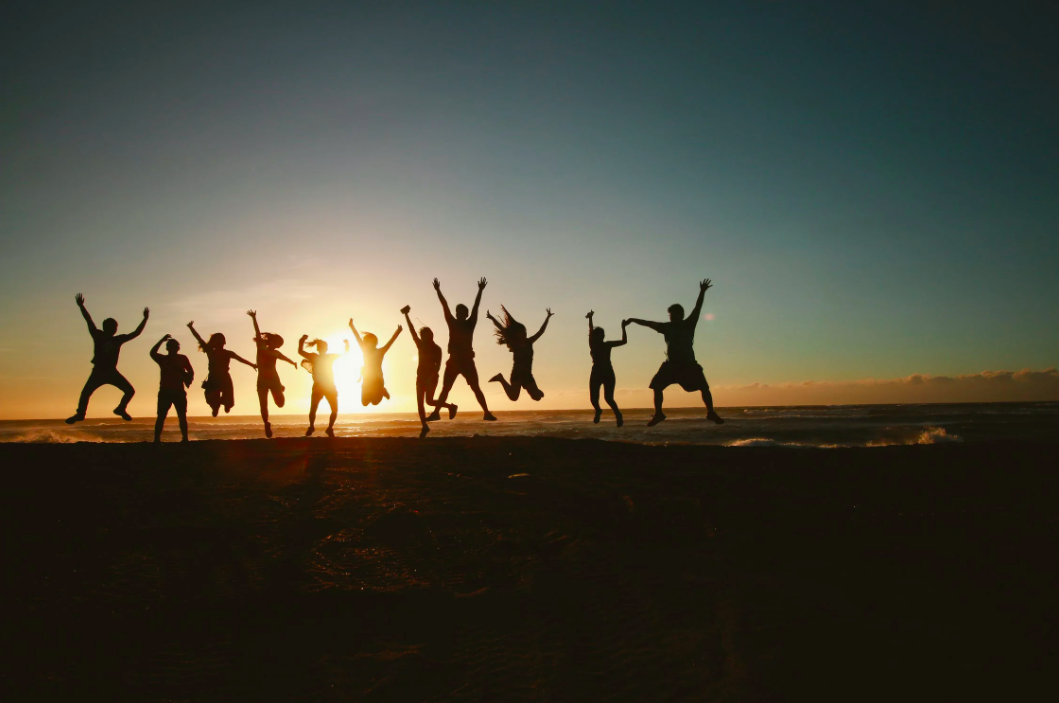 Silhouetten einer Gruppe von Menschen, die am Strand springen