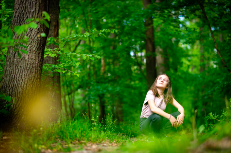 eine junge Frau, die sich im Wald ausruht und das natürliche Licht ausnutzt