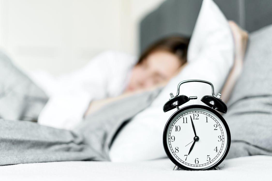alarm clock in front of a sleeping young woman