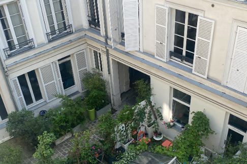 cour intérieure d’immeuble avec un jardin au rez-de-chaussée et des logements attenants sombres