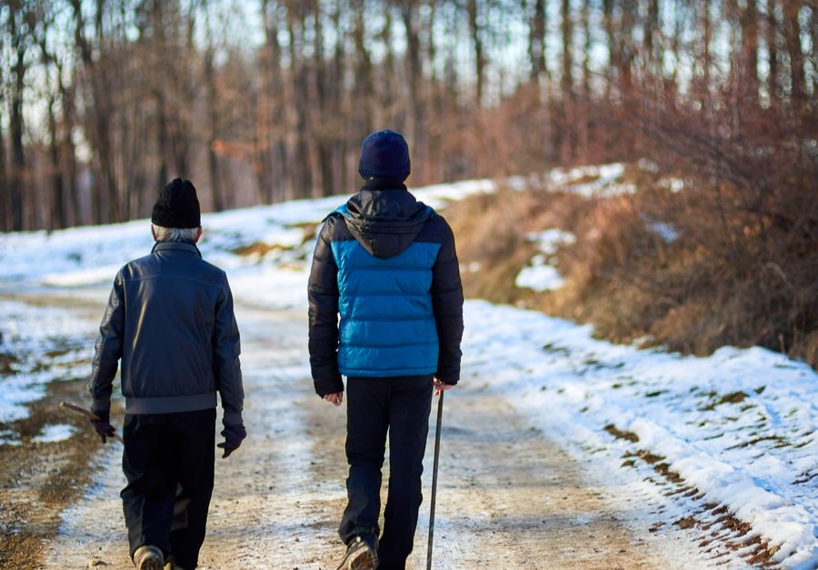two mans walking in a snowy path illuminated by the sun