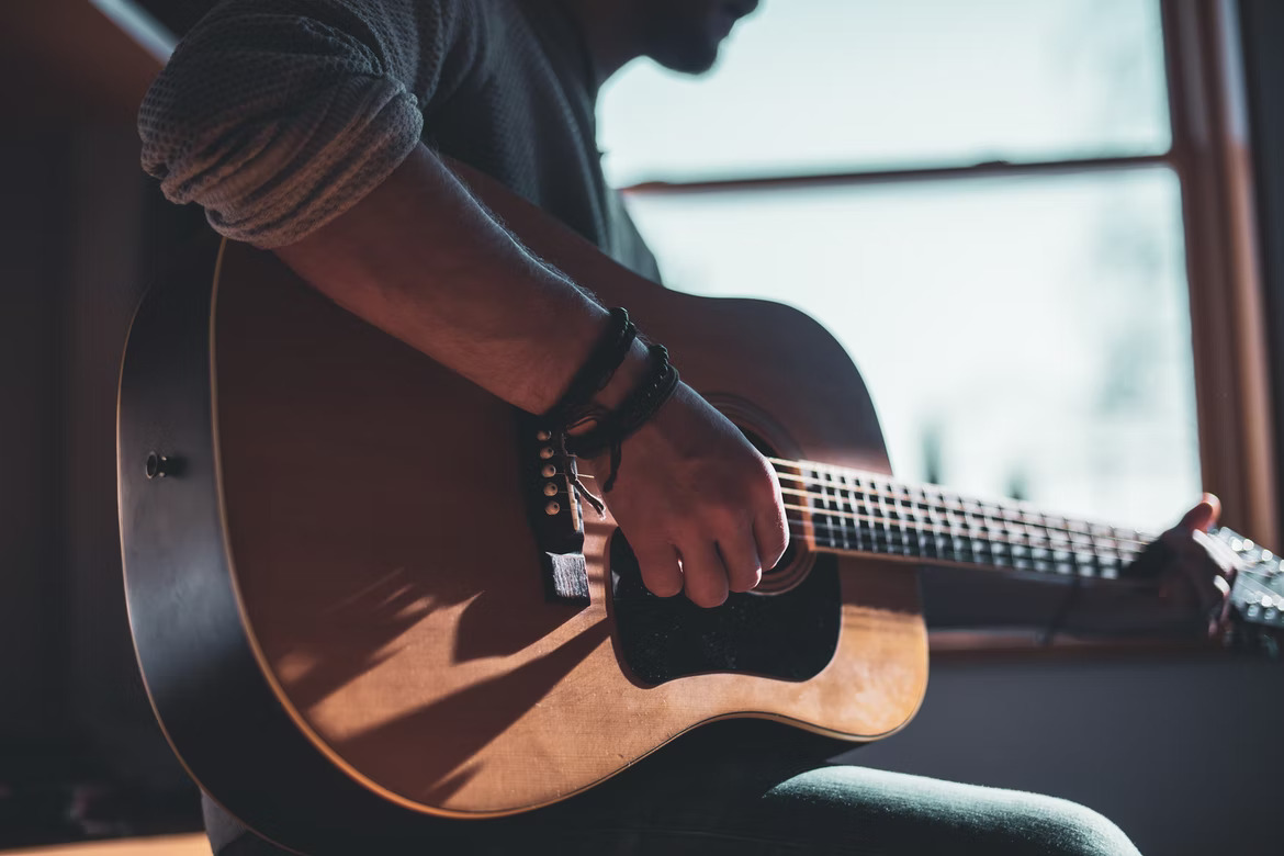 man playing guitar illuminated by the sun