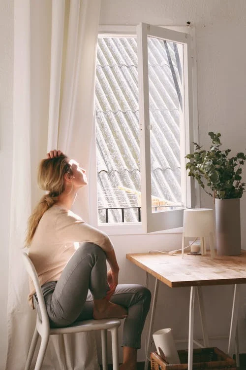 a woman illuminated by the sun is looking through the window