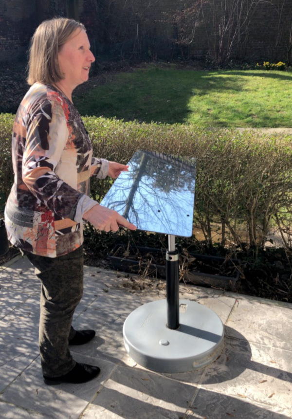Annie qui oriente le réflecteur jardin vers son rez-de-chaussée pour apporter de la lumière naturelle dans son séjour et au fond de sa cuisine