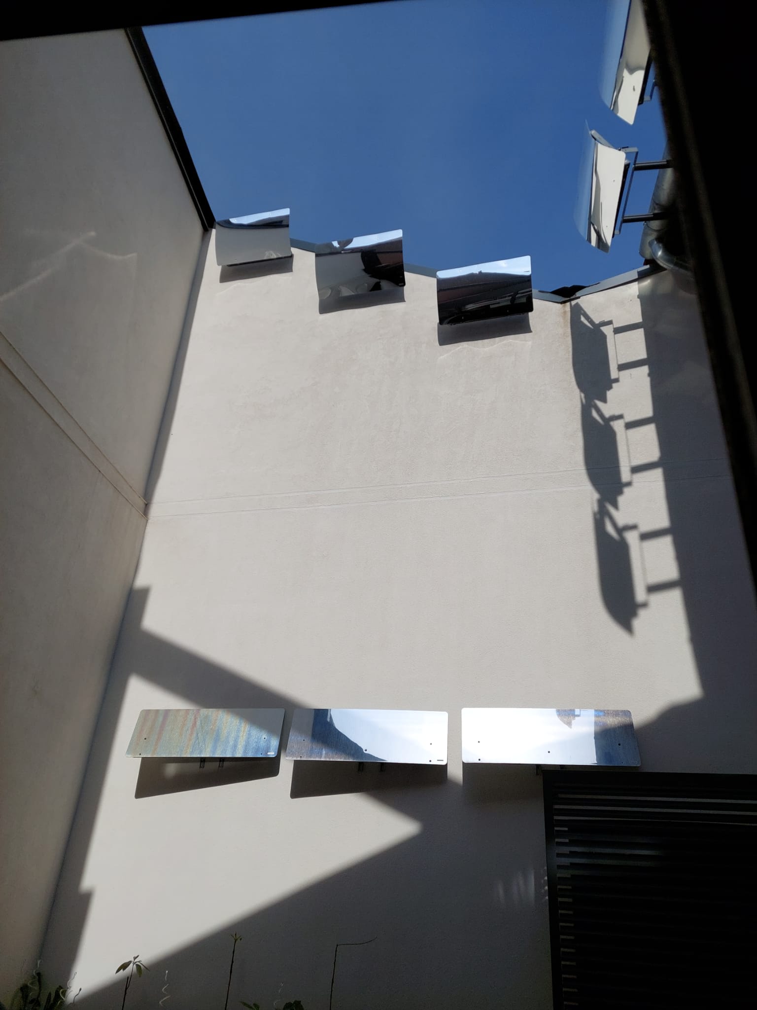 Réflecteurs Patio Solaire et Réflecteurs muraux à côté du moteur de la pompe à chaleur dans la cour intérieure