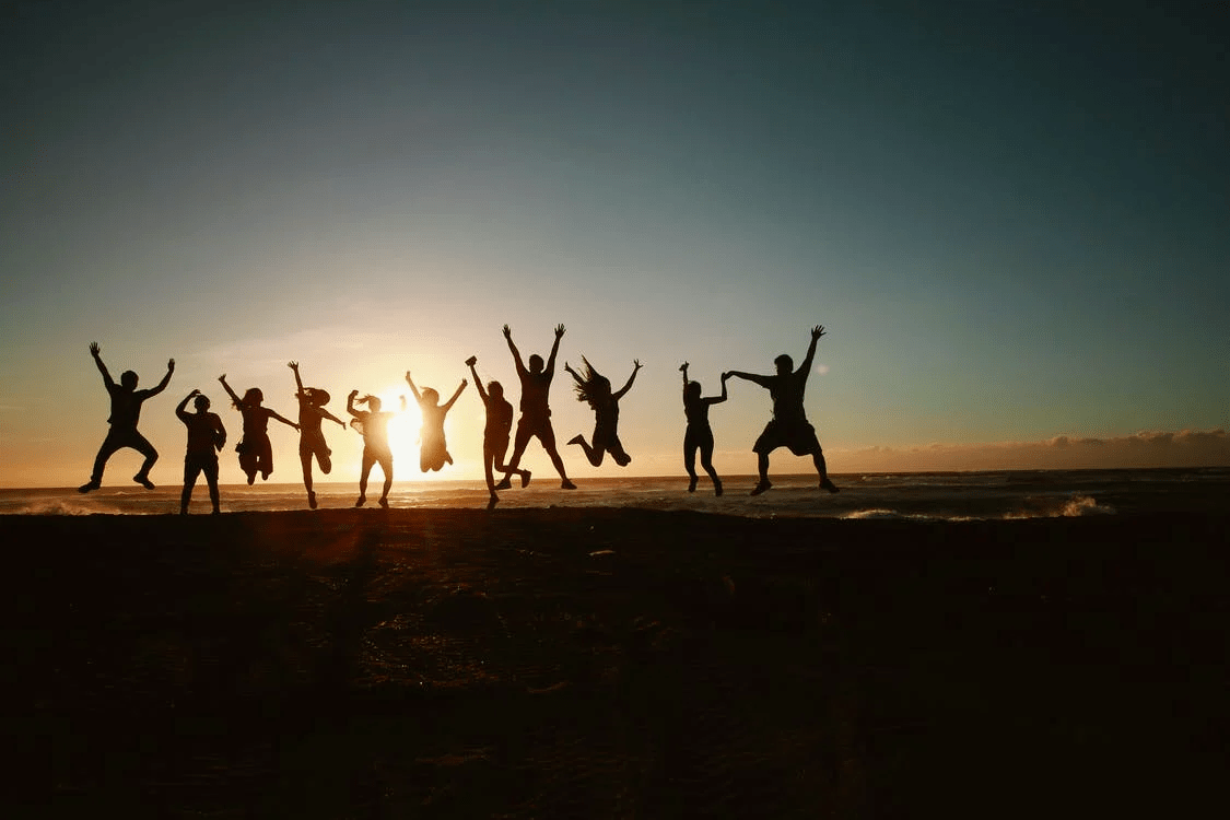 silhouettes of a group of people jumping on the beach