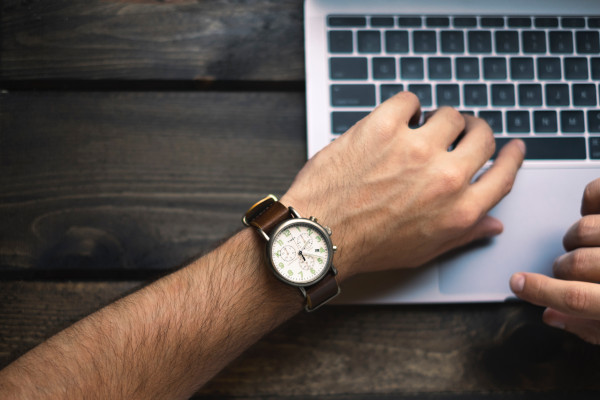 man with a watch working on his laptop