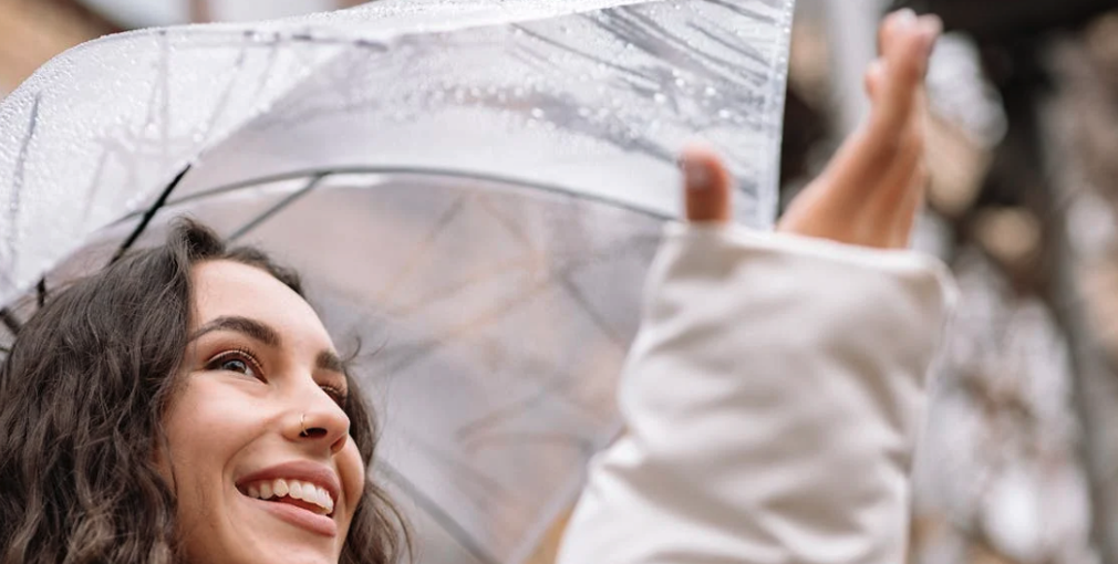 Une jeune femme heureuse profite d'une sortie pour se promener et profiter de la lumière naturelle, malgré la pluie