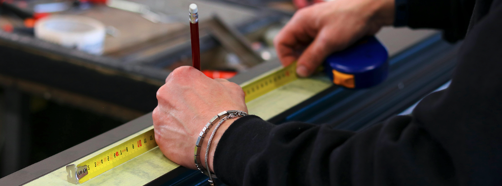 Un ouvrier de montage mesure un profilé avant de le découpé à l'atelier
