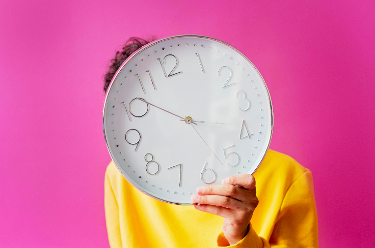 Effigie du changement d'heure d'été, un jeune homme en t-shirt jaune tient un horloge devant sa tête